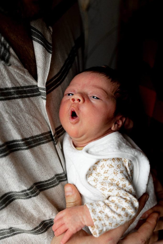 photo en gros plan d'un nouveau-né tenant le doigt de sa mère lors d'un shooting photo naissance en famille