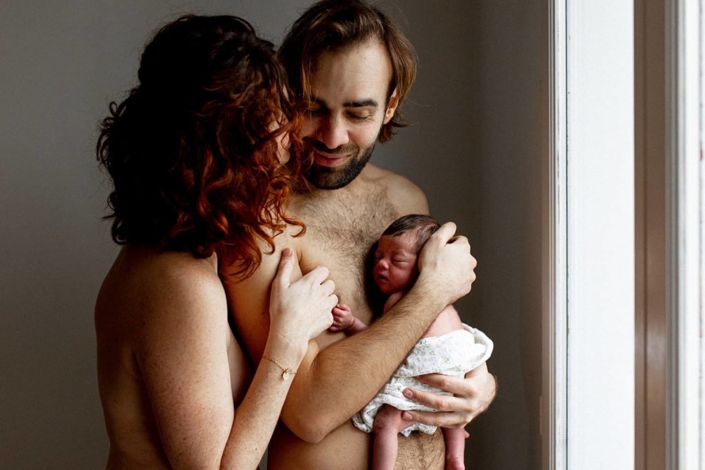 photo de famille avec un nouveau-né entouré de ses parents souriants