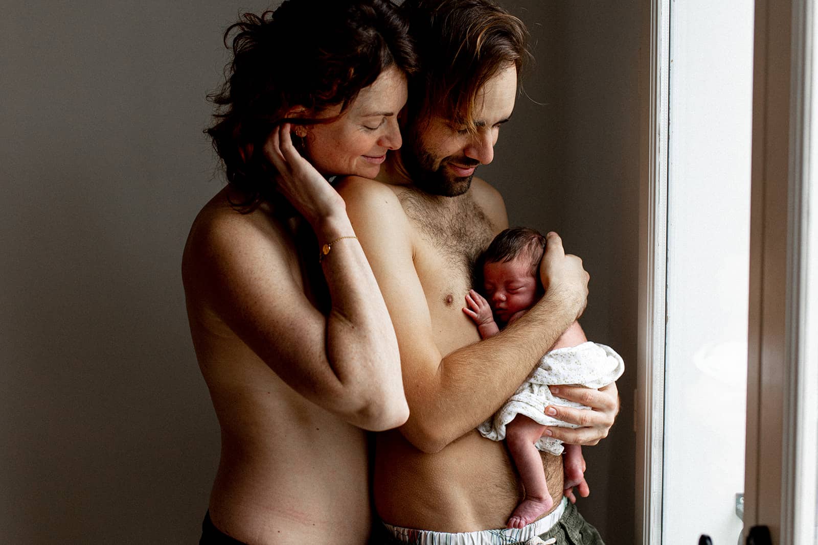 photo de famille heureuse avec le père tenant son nouveau-né contre sa peau