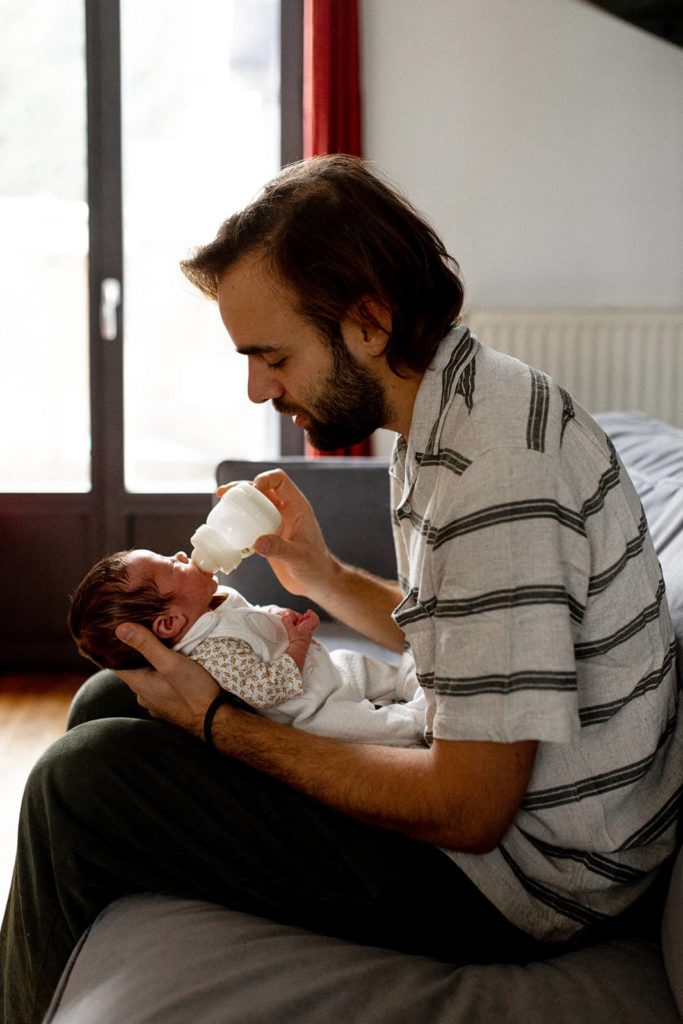 photo d'un père tenant fièrement son nouveau-né, capturant un moment de paternité tendre et émouvant